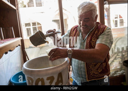 Huseyin Die Boza Hersteller von Ortahisar. Boza ist ein traditionelles Türkisches fermentiert malt Drink von bulger, Reis, Hefe und Kichererbsen mit Zimt gemacht. Kappadokien in der Türkei ist wie das Land der schönen Pferde im Herzen der anatolischen Türkei bekannt. Stockfoto