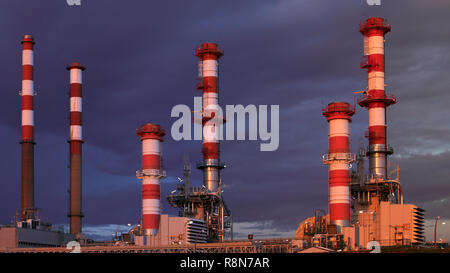 Ein Teil der vielen Schornsteine einer großen Ölraffinerie in einem bewölkten Nacht Stockfoto