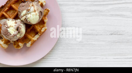 Traditionelle belgische Waffeln mit Eis auf Rosa die Platte über der weißen Holz- Oberfläche, Ansicht von oben. Kopieren Sie Platz. Stockfoto