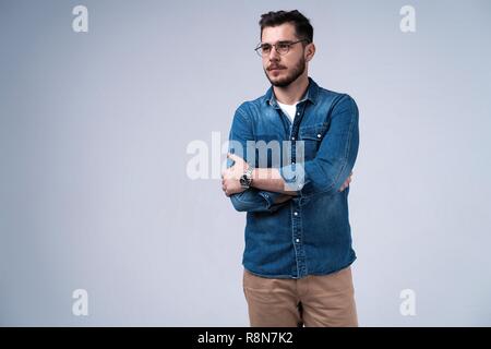 Portrait von gerne modisch gut aussehender Mann in Jeans shirt Kreuzung Hände und an der Kamera schauen. Stockfoto