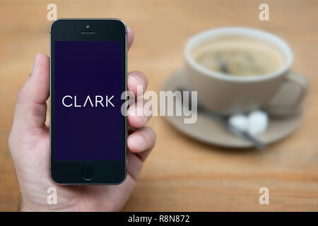 Ein Mann schaut auf seinem iPhone die zeigt die Clark Logo (nur redaktionelle Nutzung). Stockfoto