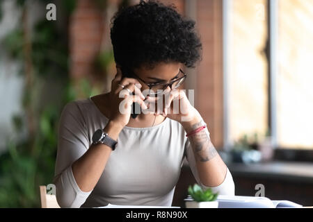 Verärgert afrikanische amerikanische Frau am Telefon sprechen, schlechte Nachrichten Stockfoto