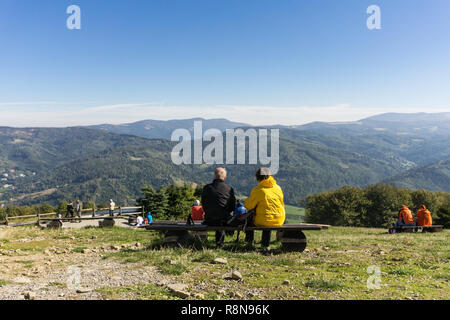 Reifes Paar ruht auf einer Bank in den Bergen an einem sonnigen Tag - Rückansicht - schöne Berglandschaft Stockfoto