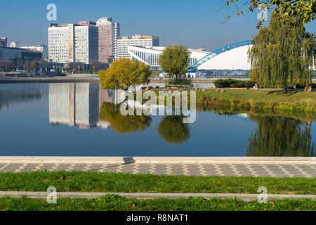 Ansicht mit Wasser Reflexionen in swislotsch Fluss - saisonale Eisbahn in der Traglufthalle, Minsk Sport Palast und mehrstöckige Häuser Stockfoto