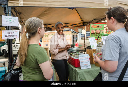 Lynn Porter, Miteigentümer von Mo'Mint & Thymian, Gespräche mit Kunden über das Unternehmen all-natürlichen Getränken am Bauernmarkt in Tucker, Georgia. Stockfoto