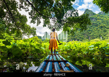 Mädchen stehen auf Bambus floss in Lotus flower See Stockfoto