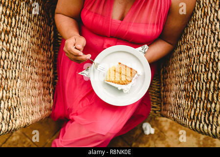 Die Frau im roten Kleid essen ein Stück Kuchen, nehmen Sie von oben Stockfoto