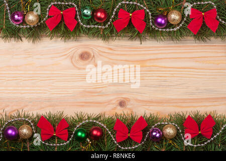 Weihnachten Rahmen aus Tannenzweigen mit roten Bögen Perlen und Kugeln auf einem hellen Hintergrund Stockfoto