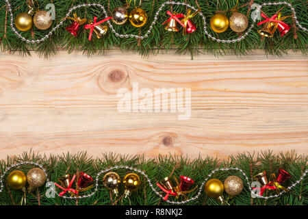 Weihnachten Rahmen aus Tannenzweigen mit Glöckchen Perlen und goldenen Kugeln auf einem hellen Hintergrund Stockfoto