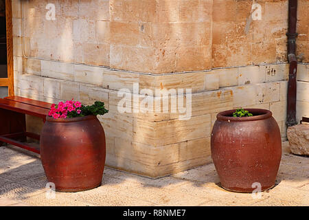 Sitzbank und Wein Schüsseln mit Blumen in der Nähe der Cana griechische orthodoxe Kirche Hochzeit in Kana in Galiläa, Kfar Kana, Israel Stockfoto