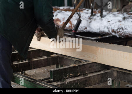 Schneiden Protokolle auf den Brettern. Im Winter wird ein Baum. Holzverarbeitung. Stockfoto