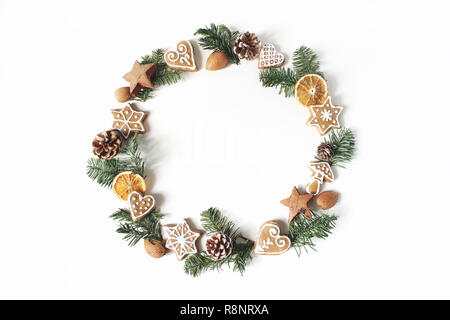 Weihnachten Kreis florale Komposition. Kranz der Tannenbaum Äste, Tannenzapfen, Gingerbread cookies und Trocknen Orangenscheiben auf weißem Hintergrund. Winterurlaub Design. Flach, Ansicht von oben. Stockfoto