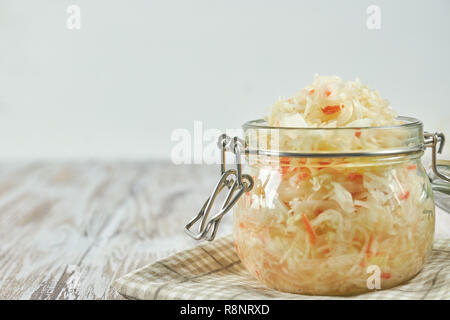 Ein Glas von Sauerkraut und Karotten im eigenen Saft mit Gewürzen auf leichte, weiße Holztisch, ein horizontaler Art von Kohl in einem jar. Traditionelle home Stockfoto