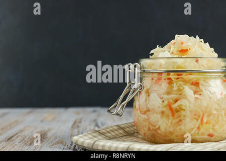 Ein Glas von Sauerkraut und Karotten im eigenen Saft mit Gewürzen auf leichte, weiße Holztisch, ein vertikaler Art von Kohl in einem jar. traditionellen Home-m Stockfoto