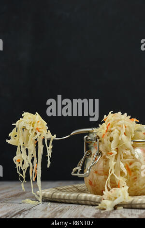 Ein Glas von Sauerkraut und Karotten im eigenen Saft mit Gewürzen auf leichte, weiße Holztisch, ein vertikaler Art von Kohl in einem jar. traditionellen Home-m Stockfoto