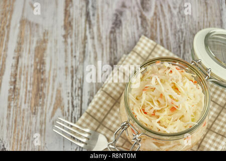 Ein Glas von Sauerkraut und Karotten im eigenen Saft mit Gewürzen auf leichte, weiße Holztisch, ein vertikaler Art von Kohl in einem jar. traditionellen Home-m Stockfoto