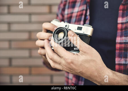 Nahaufnahme Foto Mann mit retro Foto Kamera Mode Reisen Lebensstil im Freien gegen Mauer Hintergrund. Stockfoto