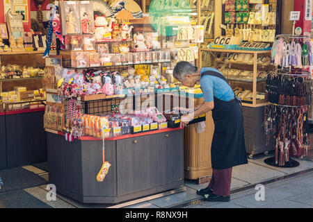 Eine ältere japanische Frau mit Souvenirs auf nakamise-dōri in der Nähe von Sensō-ji in Tokio, Japan. Stockfoto