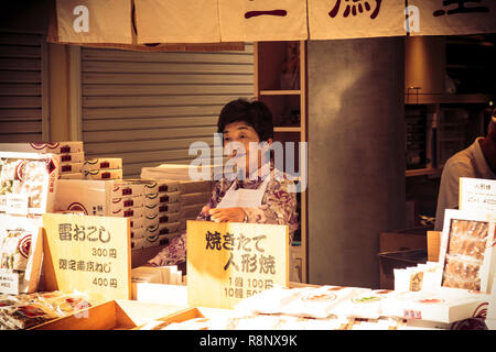 Eine ältere japanische Frau Verkauf von Snacks auf nakamise-dōri in der Nähe von Sensō-ji in Tokio, Japan. Stockfoto