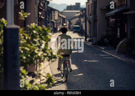 Eine ältere japanische Dame Zyklen, die eine elegante, traditionelle Straße in Kyoto, Japan. Stockfoto