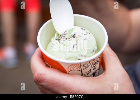 Genießen Sie eine Portion von Minze und Chocolate Chip Eis in einer Wanne mit einem Plastiklöffel serviert. Stockfoto