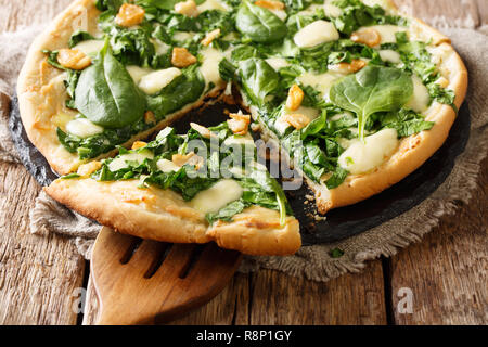 Italienische Pizza mit Spinat, Knoblauch und ricotta Käse und Mozzarella und weißer Soße close-up auf dem Tisch. Horizontale Stockfoto
