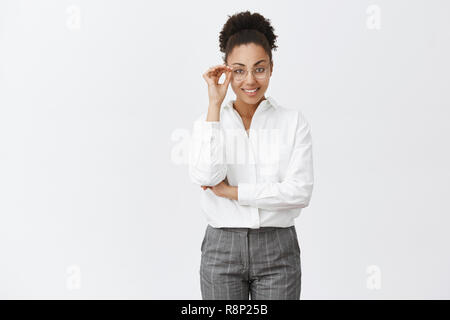 Gut aussehende stilvolle und intelligente Psychologin mit dunkler Haut in white-collar Shirt und Hose, berühren Gläser und lächelnd mit selbstbewussten Ausdruck, an der Kamera den Blick Stockfoto