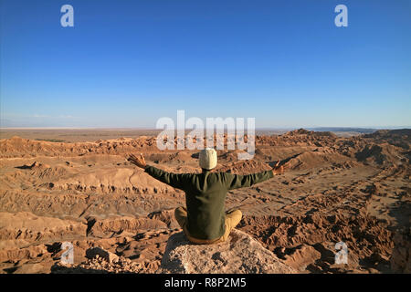 Menschen, die auf dem Felsen Anheben der Arme schätzen die herrliche Aussicht auf das Tal des Mondes oder Valle de la Luna, Atacama, San Pedro de Atacama, Chile Sitzen Stockfoto