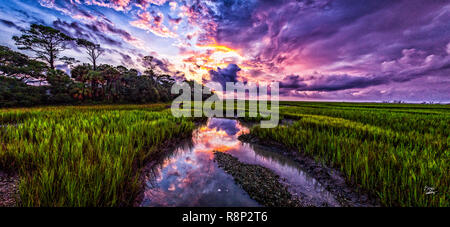 Ein dramatischer Himmel begrüsst die Sonne bei Flut in den Sumpf auf Edisto Island, South Carolina Stockfoto