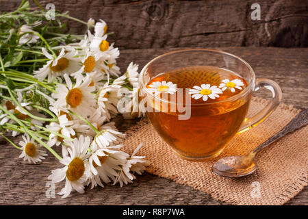 Kräutertee mit frischen Kamillenblüten auf alten hölzernen Hintergrund Stockfoto