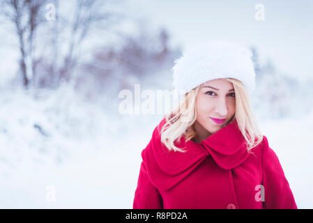 Schöne junge Frau im Winter Natur im roten Mantel Stockfoto