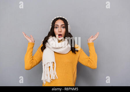 Portrait einer jungen Frau schockiert tragen Pulli und Schal isoliert über grauer Hintergrund, Achselzucken Stockfoto