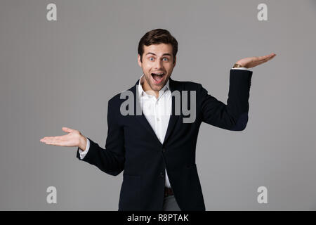 Bild von überrascht Geschäftsmann 30 s in Anzug schreien und wirft die Arme über grauer Hintergrund Stockfoto