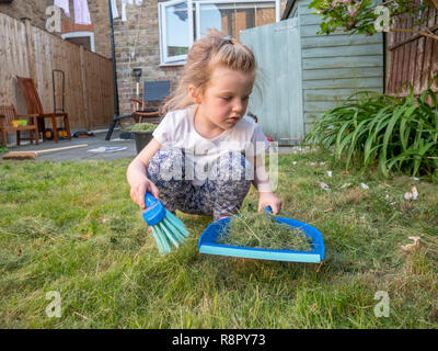 Drei Jahre alte Mädchen bis schwungvoll geschnittene Gras im Garten hinter dem Haus, London, UK Stockfoto