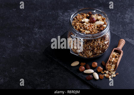 Hausgemachte gesundes Müsli aus Hafer, Nüsse und Früchte auf schwarzem Stein Background Copy space Stockfoto