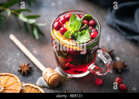 Hot spiced cranberry Tee mit Zimt, Orangenschale, Sternanis und Honig im Glas Schale Stockfoto