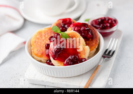 Quark Krapfen oder syrniki mit Preiselbeersoße auf weiße Platte, Detailansicht. Schmackhaftes süßes Frühstück essen Stockfoto