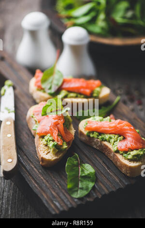 Lachs und Avocado Toast, gesunde Vorspeise oder Snack auf Holz boarc dienen. Detailansicht Stockfoto