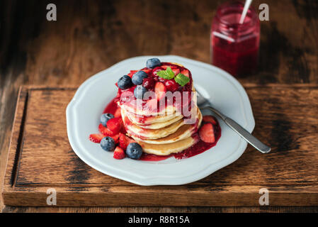 Pfannkuchen mit Beeren Sauce und frische Beeren auf Holz serviert. Leckeres Frühstück oder Dessert Stockfoto
