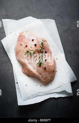 Hähnchenfilet mit Gewürzen und Rosmarin auf einem dunkelgrauen Oberfläche. Ansicht von oben. Stockfoto