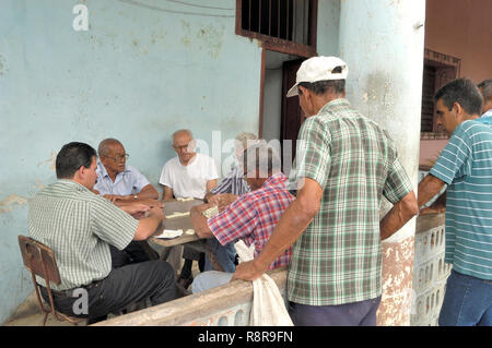 Trinidad, Cuba-April 04,2016: Männer Domino spielen auf der Straße, während andere Männer sehen Sie Stockfoto