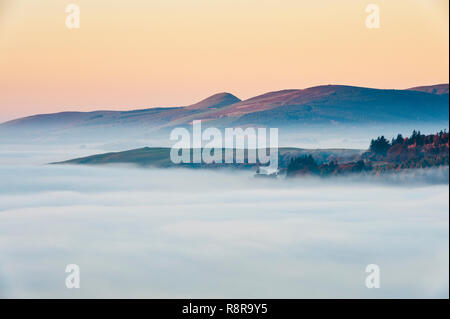An der walisischen Grenze in der Nähe von Knighton, Powys, UK. Am frühen Morgen über West von Stonewall Hügel, die die Täler mit dichten Nebel gefüllt Stockfoto