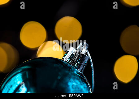 Blaues Glas weihnachtskugel's Detail vor dem Bokeh Lichter, dunkle Fotografie Konzept. Weihnachtsschmuck für Weihnachtskiefer. Stockfoto