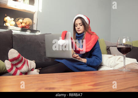 Lonely Girl in einem Weihnachten Gap ist das Trinken von Wein, auf dem Laptop zu Hause arbeiten Stockfoto