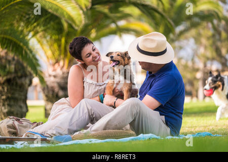 Kaukasische Paar genießen und spielen mit ein wenig pet Shetland Hund jung und verspielt-park Outdoor Freizeitaktivitäten Aktivität für fröhliche Menschen Lächeln und cheeers wi Stockfoto