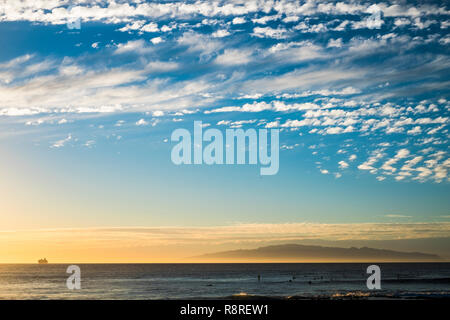 Sonnenuntergang auf dem Meer mit Fähre Bootsfahrt am Horizont reisen und Surfer auf dem Wasser warten auf einige Wellen zu trainieren und die aktive genießen Stockfoto