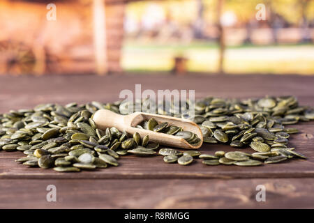 Menge ganze geschälte Kürbiskerne mit Holz- Schaufel mit Karre im Hintergrund Stockfoto