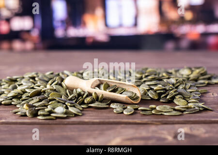 Menge ganze geschälte Kürbiskerne mit Holz- Schaufel mit Restaurant im Hintergrund Stockfoto