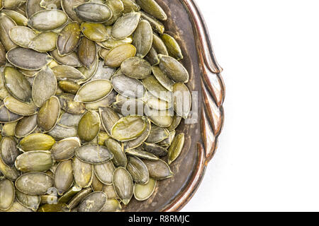 Nahaufnahme der Menge ganze geschälte Kürbiskerne in Altes Eisen Schüssel flatlay auf weißem Hintergrund Stockfoto