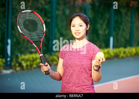 Outdoor portrait einer jungen asiatischen Tennisspieler an der Kamera schaut lächelnd Stockfoto